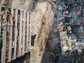 Une vue aérienne montre des pompiers travaillant dans les décombres d'un immeuble résidentiel qui a été touché par les débris d'une roquette abattue à Kiev le 17 mars 2022.