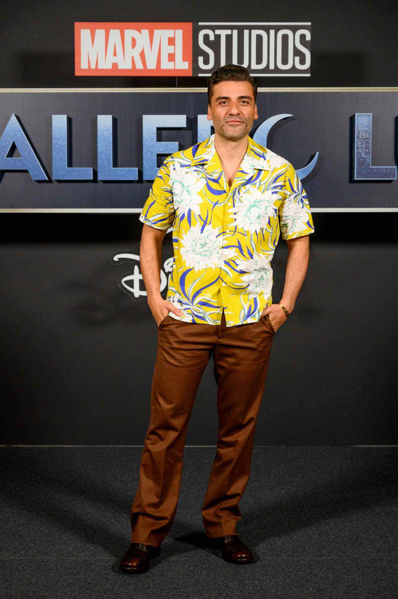 Oscar Isaac debout dans une chemise hawaïenne jaune, avec un pantalon en cuivre, à la première de Spain Moon Knight.
