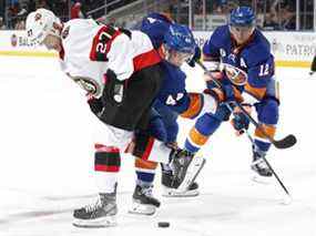 Dylan Gambrell des Sénateurs d'Ottawa combat Jean-Gabriel Pageau # 44 et Josh Bailey # 12 des Islanders de New York pour la rondelle lors de la deuxième période à l'UBS Arena le 22 mars 2022 à Elmont, New York.