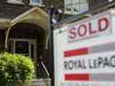 Une enseigne à vendre d'un agent immobilier se trouve à l'extérieur d'une maison qui a été vendue à Toronto.