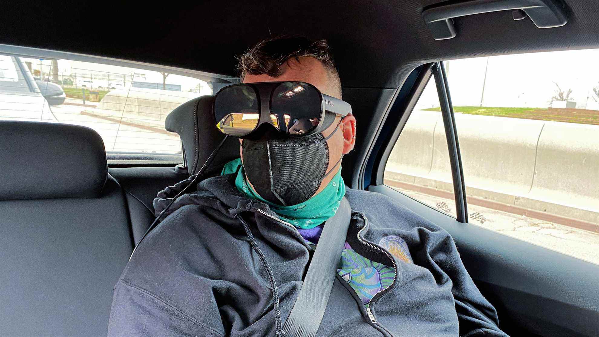 Femme assise sur le siège arrière de la voiture portant un casque VR