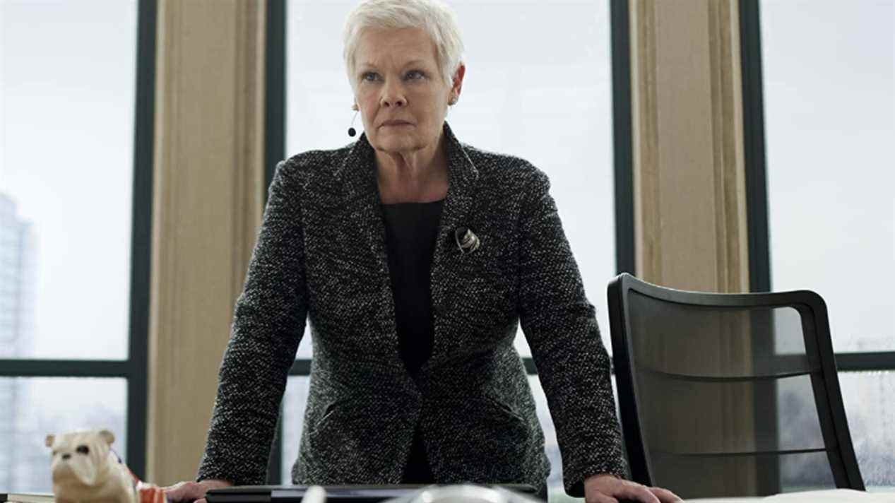 Dame Judi Dench debout à son bureau, avec Jack le Bouledogue dans Skyfall.