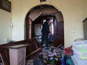 Un parent aide à nettoyer l'appartement d'Olena Zaichenko, qui a été détruit à la suite d'une frappe de missile sur le quartier résidentiel, le 18 mars 2022 à Kiev, en Ukraine.