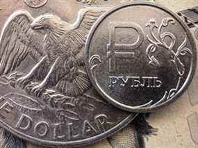 Une pièce de monnaie en rouble russe avec une pièce de un dollar américain.  Le président russe Vladimir Poutine a ordonné à Gazprom d'accepter le paiement en roubles pour ses exportations de gaz naturel vers l'Europe.