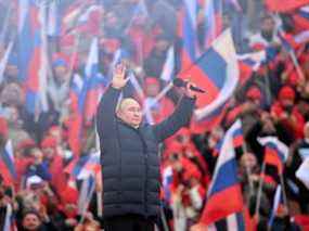 Le président Vladimir Poutine salue lors d'un rassemblement marquant le huitième anniversaire de l'annexion de la Crimée par la Russie, au stade Luzhniki de Moscou, en Russie, le 18 mars 2022.