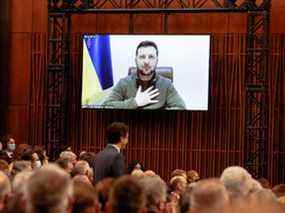 Des membres de la Chambre des communes et du Sénat écoutent le président ukrainien Volodymyr Zelenskyy, qui apparaît sur un écran, s'adresser au Parlement canadien à Ottawa, le 15 mars 2022.