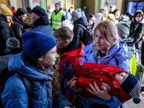 Une femme tient un enfant endormi alors que des réfugiés attendent d'être transportés à la gare de Przemysl, en Pologne, le 17 mars 2022.