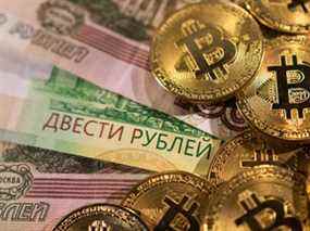 Billets en roubles russes et représentations de la crypto-monnaie Bitcoin.