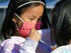 Tessa Ng (à gauche, 5 ans) aide son amie Liv Leong (5 ans) à mettre un masque facial pendant la pandémie de COVID-19 à Edmonton.  Le 19 novembre 2021
