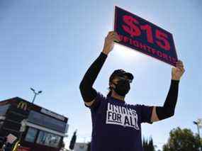 Un homme brandit un signe de salaire minimum lors d'un rassemblement organisé par des travailleurs et des partisans de la restauration rapide à Los Angeles, en Californie.