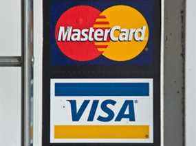 Dans cette photo d'archive prise le 30 mars 2012, les logos des cartes de crédit Visa et MasterCard sont visibles dans la vitrine d'un magasin à Washington, DC.