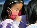 Tessa Ng, 5 ans, aide un ami à mettre un masque facial sur une photo d'archive d'Edmonton du 19 novembre 2021. Certains médias se sont fait alarmistes concernant les risques posés par le coronavirus aux enfants, disent trois experts.