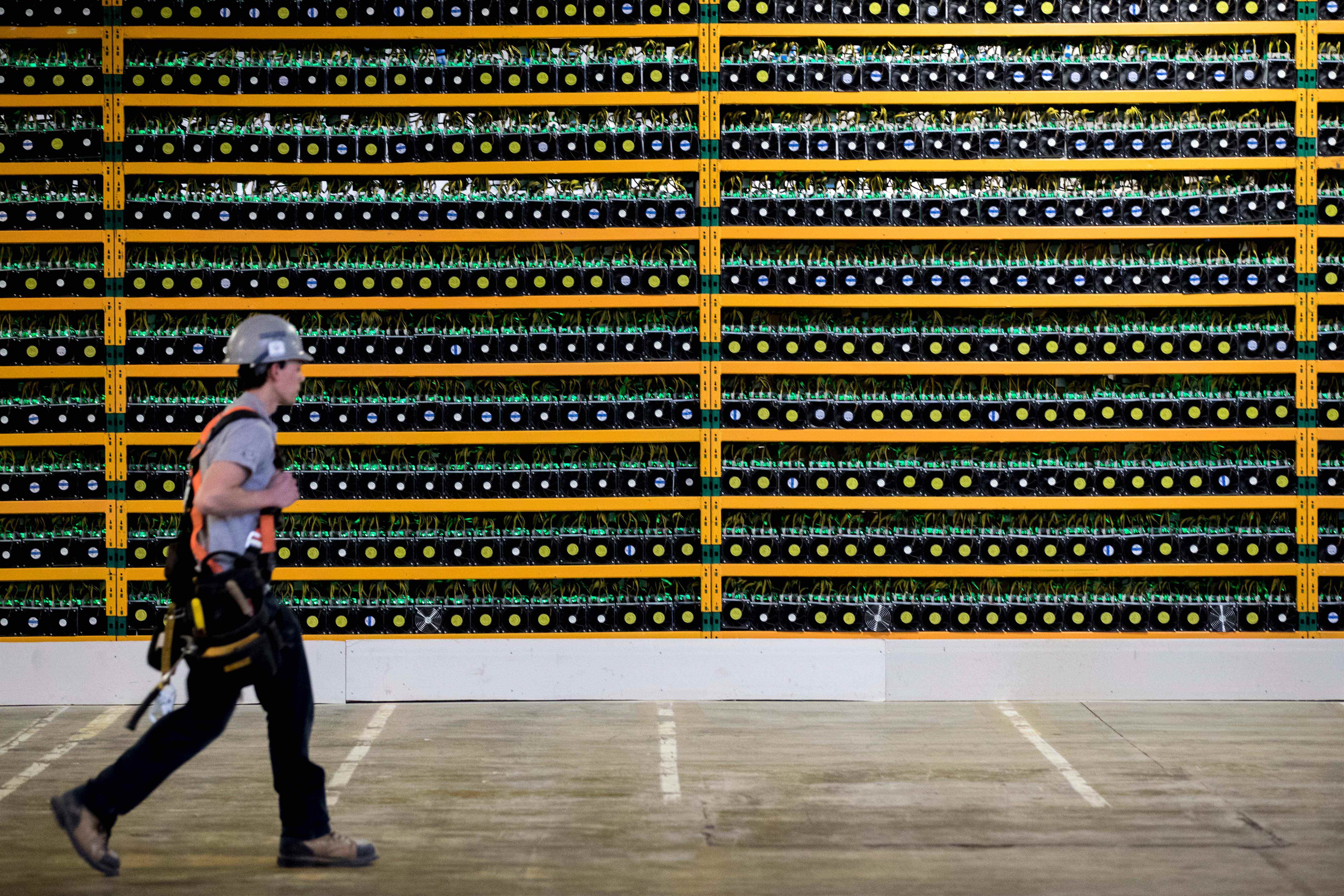 Image d'une personne passant devant un mur de plates-formes minières Bitcoin