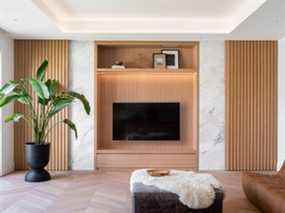 Le téléviseur peut être dissimulé derrière des lattes verticales en bois dans le meuble multimédia.  Les planchers à chevrons en chêne blanc sont liés aux éléments en bois pâle utilisés dans toute la maison.