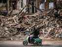 Un homme conduit un scooter devant les décombres d'un bâtiment détruit dans la ville de Kharkiv, dans l'est de l'Ukraine, le 2 avril 2022, alors que l'Ukraine a déclaré aujourd'hui que les forces russes faisaient un 