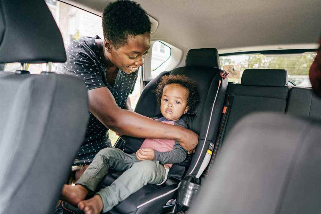 un parent attache un enfant dans un siège d'auto orienté vers l'avant
