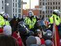 Des manifestants se tiennent devant des policiers canadiens à cheval, alors que des camionneurs et des partisans continuent de protester contre les mandats de vaccination contre la maladie à coronavirus (COVID-19), à Ottawa, Ontario, Canada, le 18 février 2022.
