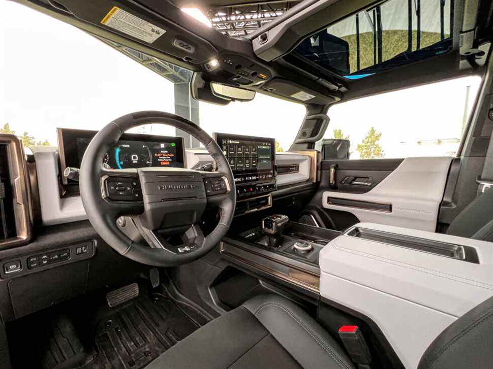 L'intérieur du Hummer EV a un style audacieux, avec des accents robustes pour des éléments comme les écrans d'affichage.  Il y a un levier de transmission conventionnel et de gros boutons physiques pour les commandes de climatisation et pour changer les modes de conduite.  Et les panneaux de toit sont amovibles.