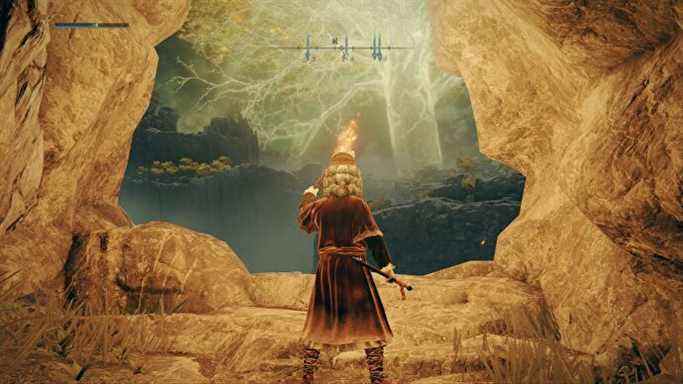 Joueur Elden Ring tenant une torche alors qu'ils quittent Coastal Cave, Great Erdtree towers à l'horizon