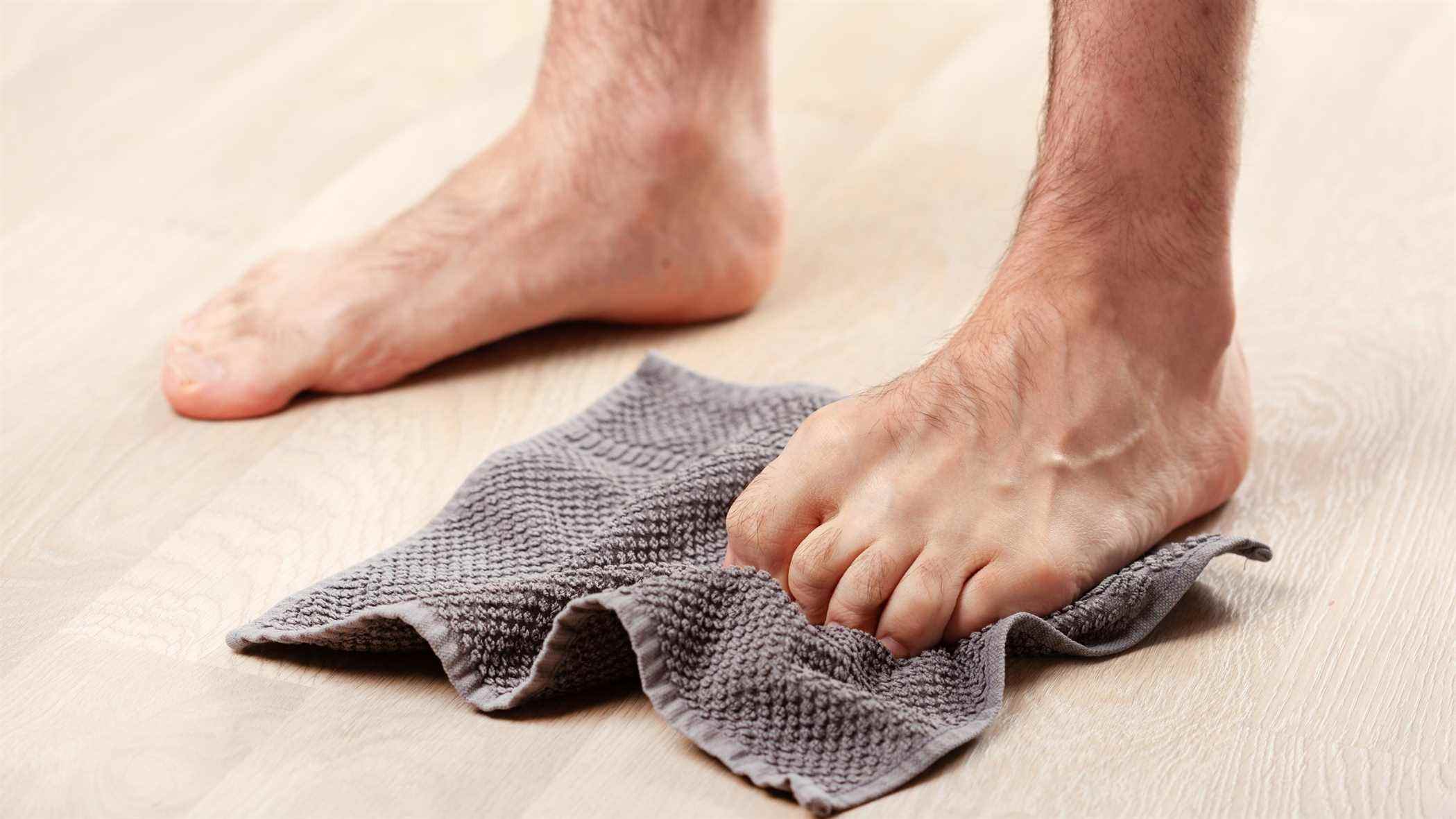 un homme frottant ses orteils sur une serviette