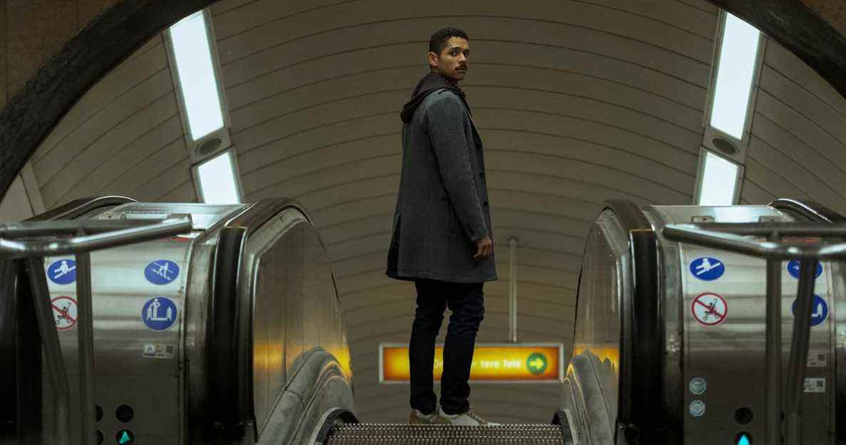 Alan debout sur un escalator dans une station de métro