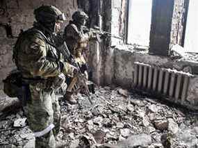 Deux soldats russes patrouillent dans le théâtre dramatique de Marioupol, bombardé le 16 mars dernier, à Marioupol, en Ukraine, le 12 avril 2022.