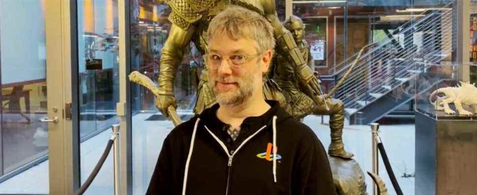 Cory Barlog stood in front of a statue of Kratos and Atreus