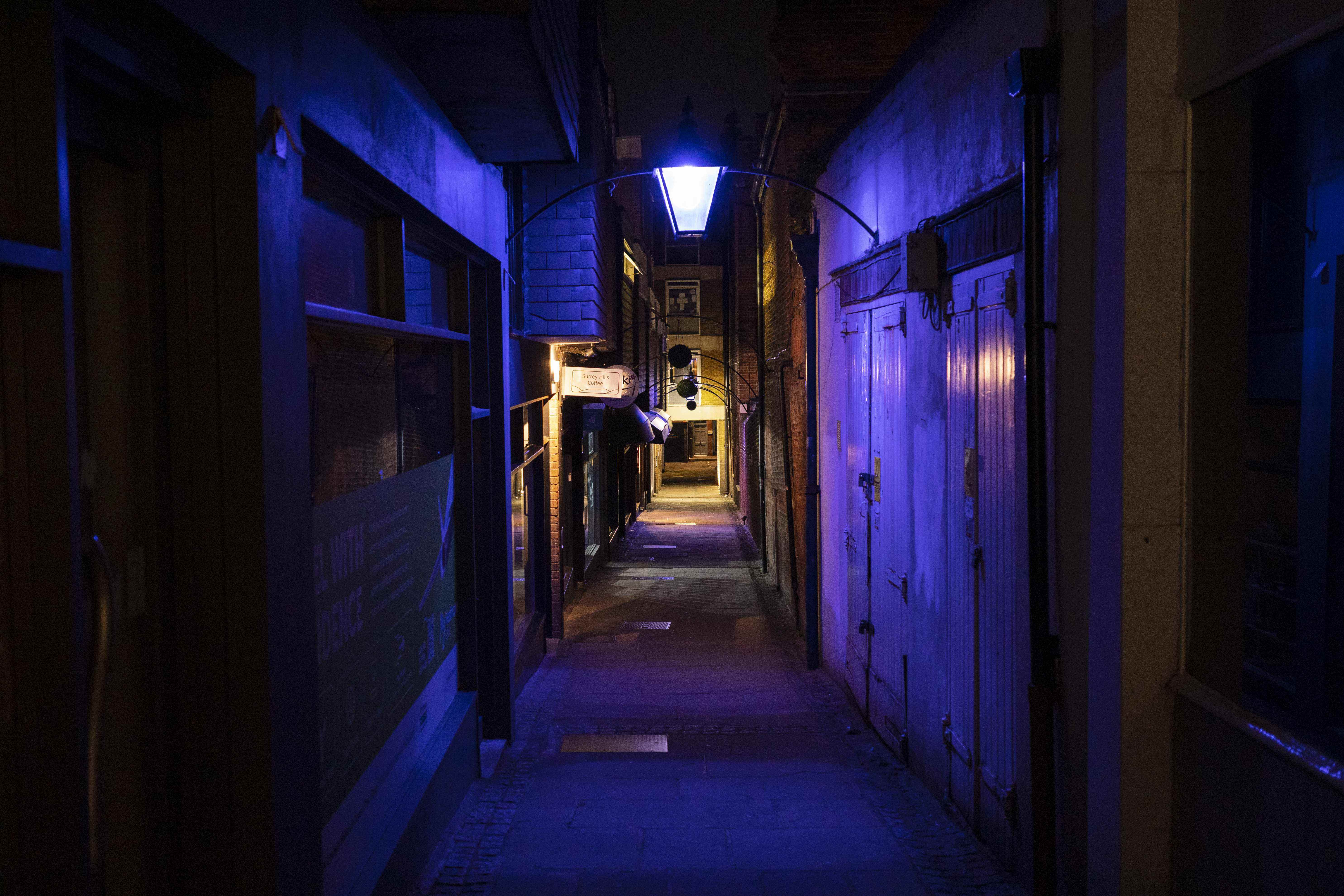 Une ruelle étroite éclairée par des lumières violettes artificielles
