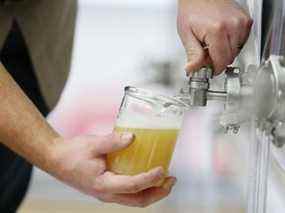 Un technicien verse un échantillon de bière partiellement fermentée dans un bécher au Centre technique canadien de l'orge brassicole à Winnipeg.