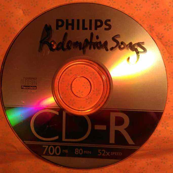 Une photographie d'un CD-R avec l'étiquette manuscrite 'Redemption Songs'.
