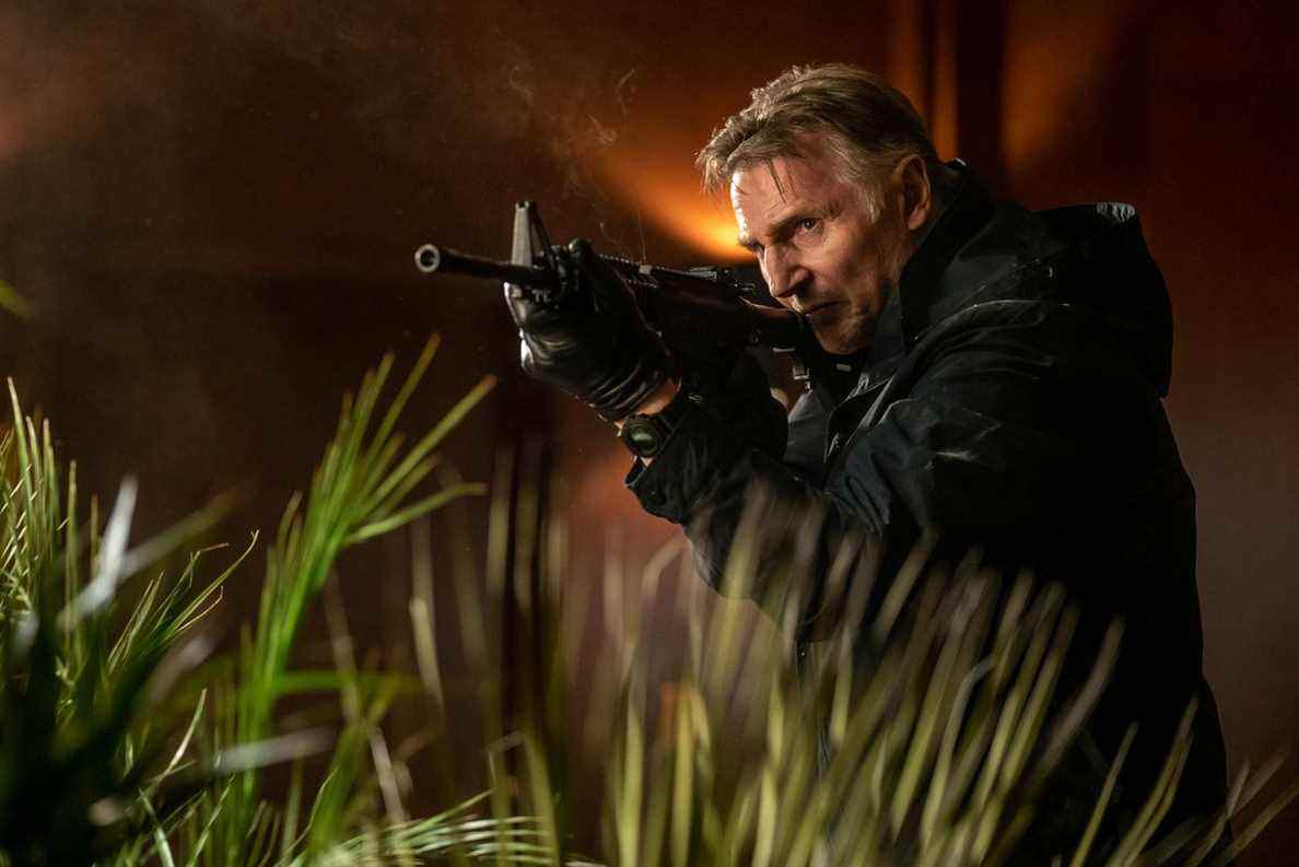 Liam Neeson traverse les hautes herbes avec un fusil d'assaut dans Memory