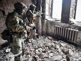 Deux soldats russes patrouillent dans le théâtre dramatique de Marioupol, bombardé le 16 mars dernier, à Marioupol le 12 avril 2022.