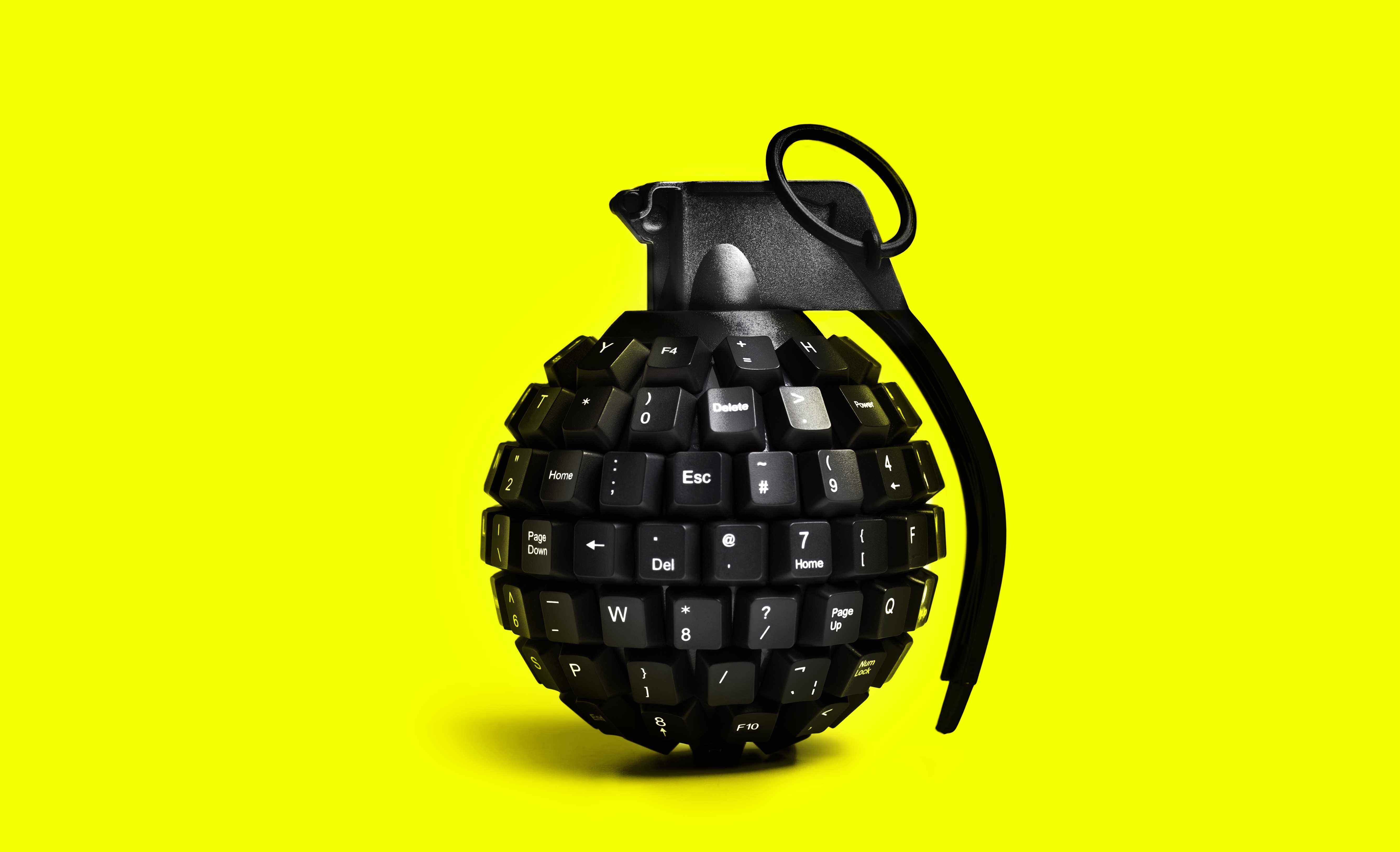 Image d'une grenade fabriquée à partir de clés d'ordinateur sur un fond jaune fluo.