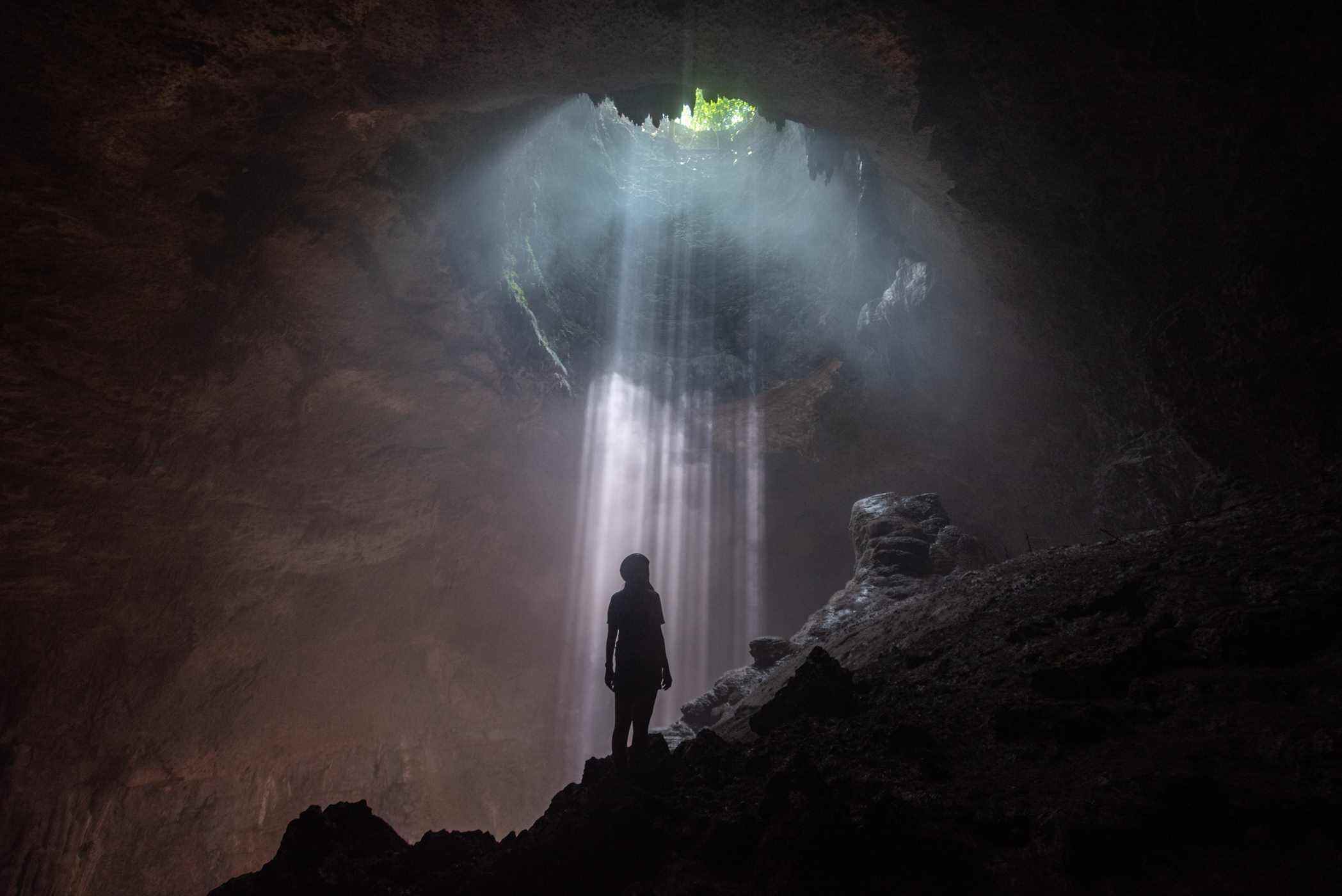Femme regardant l'ouverture dans la grotte de Jomblang