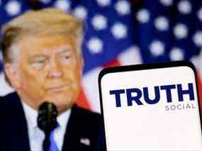 Le logo du réseau Truth Social est visible sur un smartphone devant un écran de l'ancien président américain Donald Trump dans cette illustration prise le 21 février 2022.