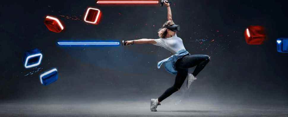 A woman in white t-shirt and sneakers wearing a VR headset leaps towards approaching red and blue blocks, her arms stretched behind her holding two lightsabesr