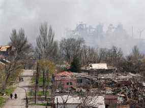 De la fumée s'élève au-dessus d'une usine de la société Azovstal Iron and Steel Works et de bâtiments endommagés au cours du conflit Ukraine-Russie dans la ville portuaire méridionale de Marioupol, Ukraine, le 18 avril 2022.