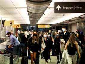 Les voyageurs portant des masques de protection pour empêcher la propagation du COVID-19 récupèrent leurs bagages à l'aéroport de Denver, Colorado, le 24 novembre 2020.