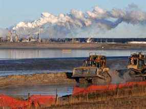 Des travailleurs utilisent de la machinerie lourde dans le bassin de résidus de l'installation d'extraction des sables bitumineux de Syncrude près de la ville de Fort McMurray en Alberta le 25 octobre 2009.