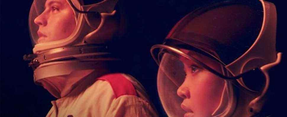 Guy and girl in astronaut suit glow with red hue.