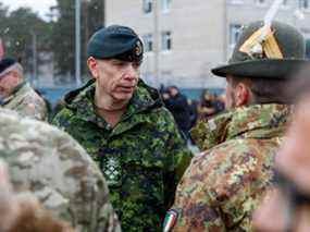 Le général Wayne Donald Eyre, chef d'état-major de la Défense (CEMD) du Canada, s'entretient avec des soldats lors d'une visite de la base militaire d'Adazi, au nord-est de Riga, en Lettonie, le 8 mars 2022.
