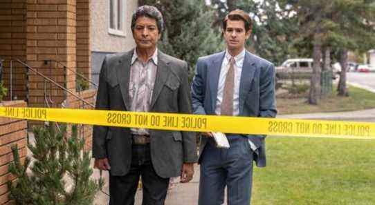 Two men stand in front of crime scene tape.