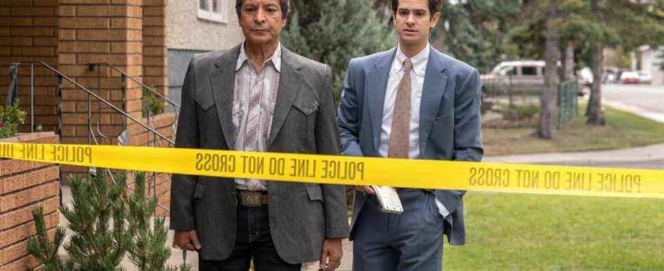 Two men stand in front of crime scene tape.