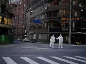 Des travailleurs en tenue de protection surveillent une rue lors d'un verrouillage à Shanghai, le 16 avril.