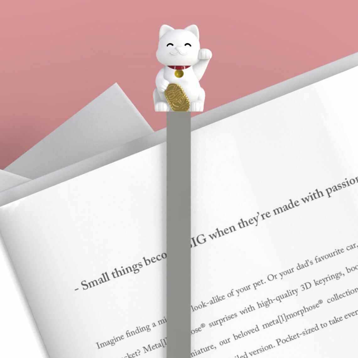 Image d'un signet de chat porte-bonheur blanc sur un livre ouvert. 