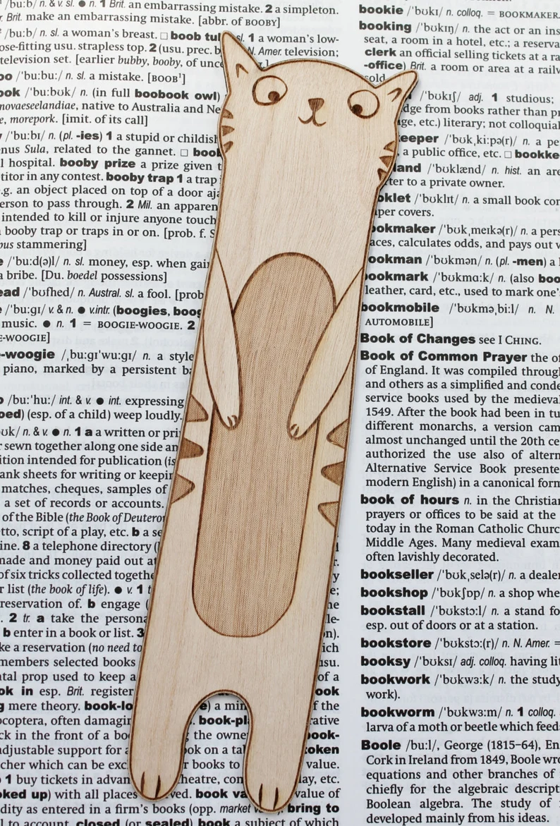 Image d'un signet de chat en bois au-dessus d'une page de dictionnaire ouverte aux mots sur le thème du livre. 