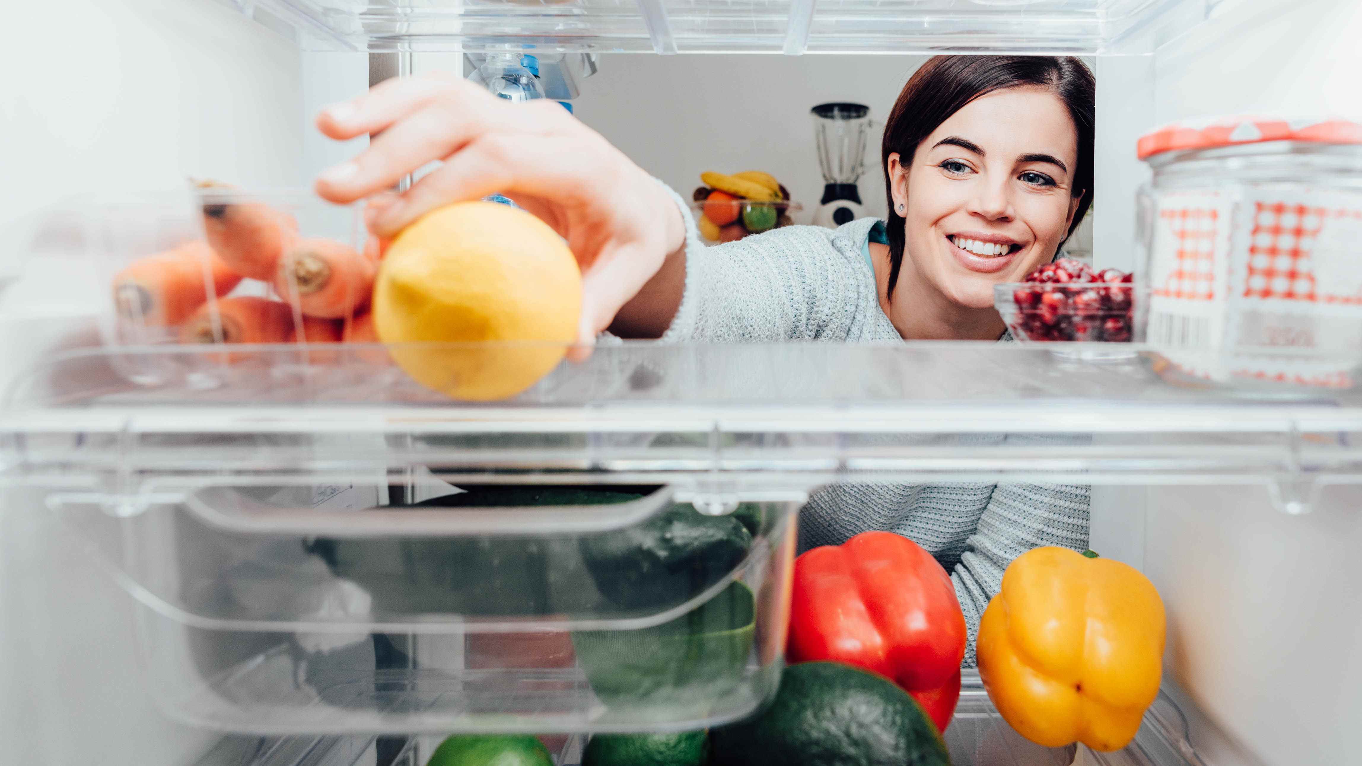 Femme regardant à l'intérieur du réfrigérateur