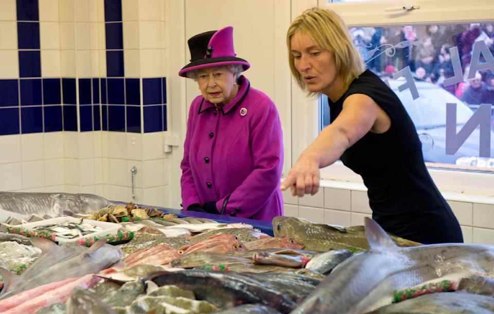 La reine Elizabeth II se voit montrer certains des poissons par le gérant du magasin Kerry Biggerstaff alors qu'elle visite le marché aux poissons de Newhaven, West Quay Fisheries le 31 octobre 2013 à Newhaven, East Sussex, Angleterre.  (Photo par Arthur Edwards - Piscine WPA/Getty Images)