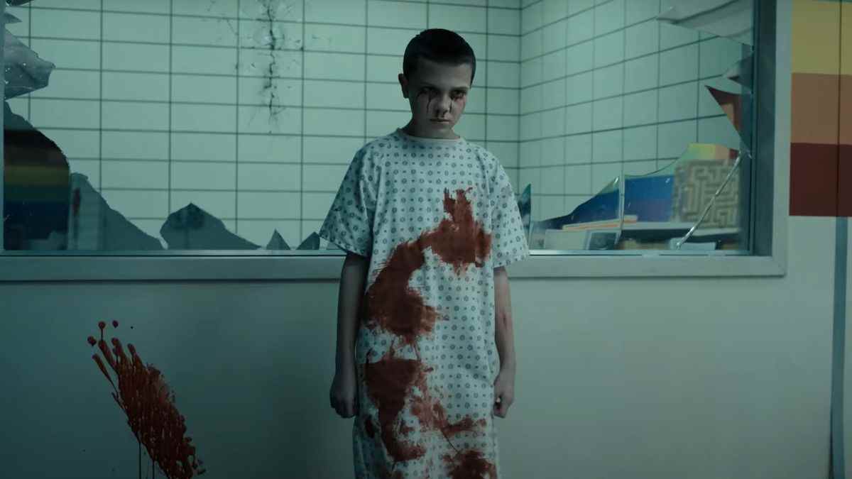 Un jeune Onze se tient couvert de sang, luisant devant un miroir sans tain dans la Rainbow Room du Hawkins Lab.