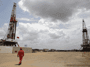Un ouvrier pétrolier marche à côté des plates-formes de forage d'un puits de pétrole exploité par la compagnie pétrolière d'État vénézuélienne PDVSA.